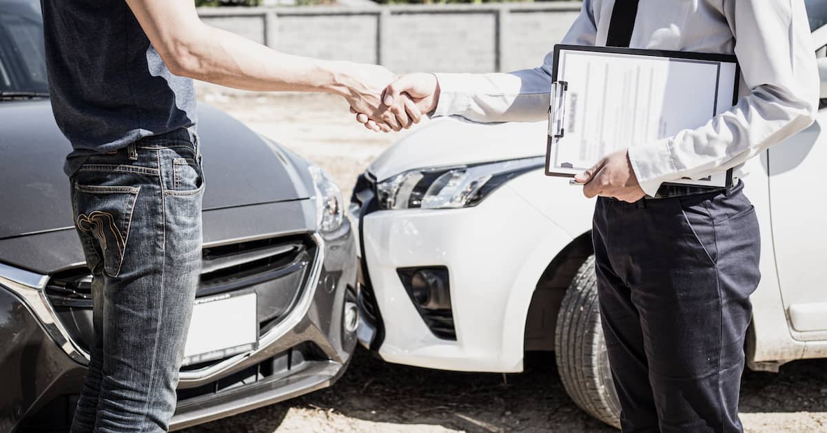 Motorist getting car accident report and shaking hands with insurance adjuster | Burg Simpson