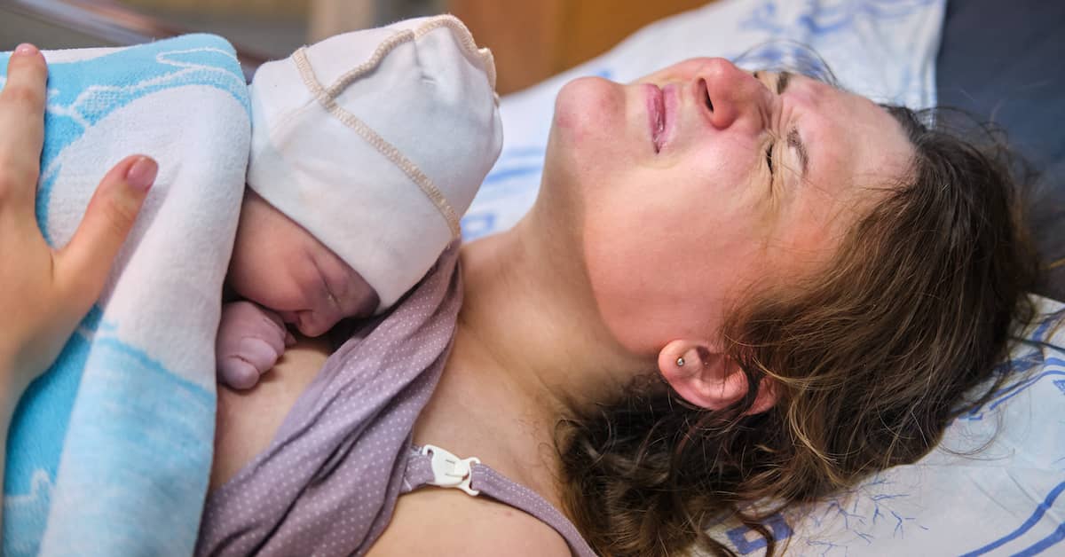 New mother wincing in pain due to postpartum hemorrhage | Burg Simpson