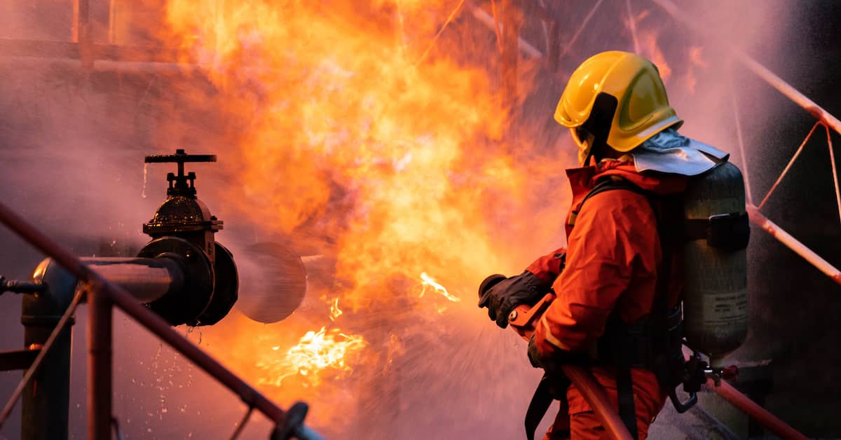 Firefighter spraying water on burst gas line | Burg Simpson