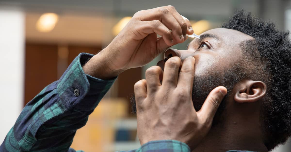 man uses eye drops | Burg Simpson