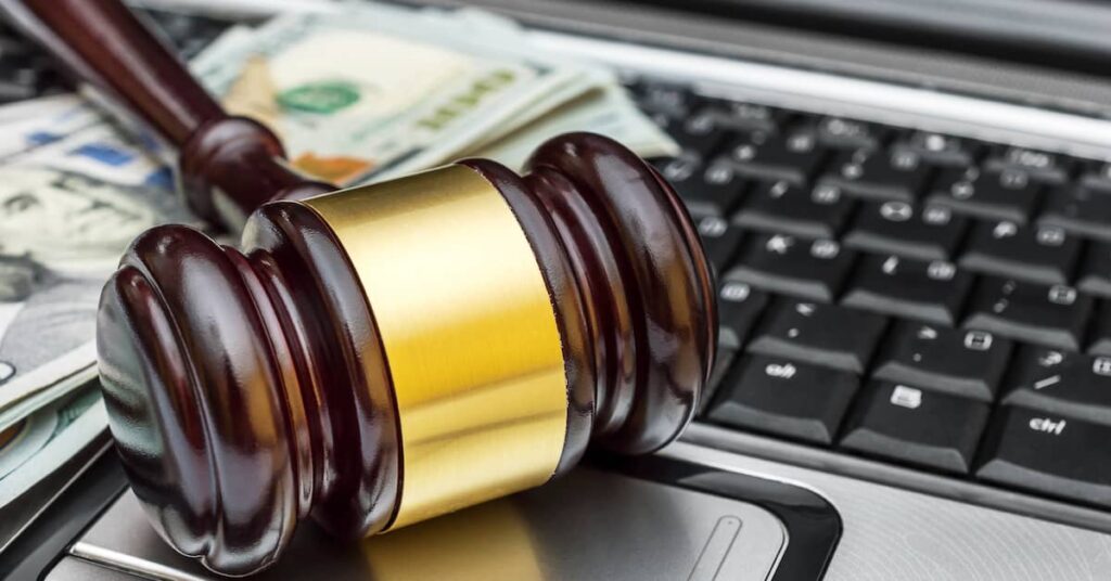 Money and gavel sitting on a laptop computer | Burg Simpson