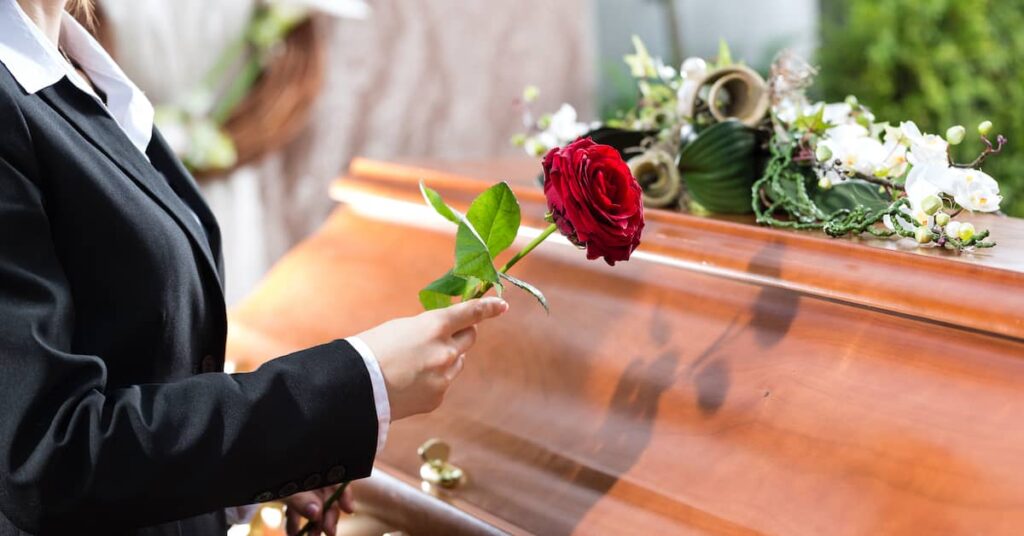 Woman laying a flower on the casket of a deceased loved one | Burg Simpson