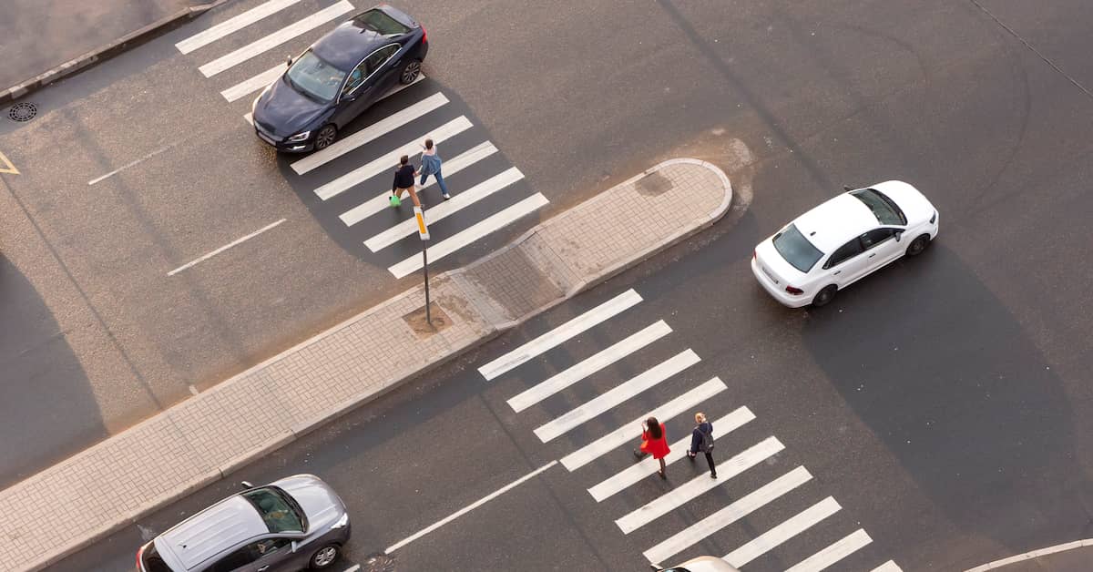 Pedestrians crossing the road at a busy two-way intersection | Burg Simpson