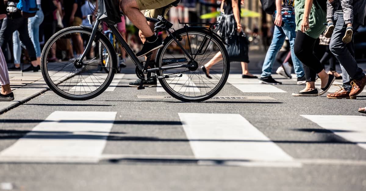 Pedestrians and bicyclists in a crosswalk on busy street | Burg Simpson