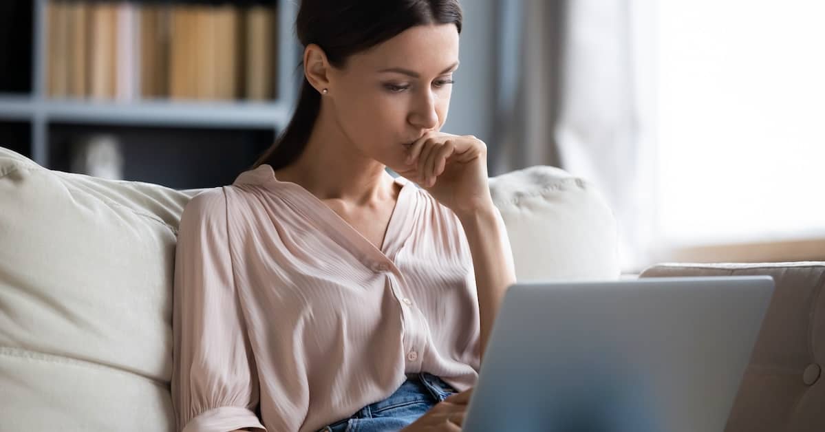 Young woman looking up an accident report on her laptop | Burg Simpson