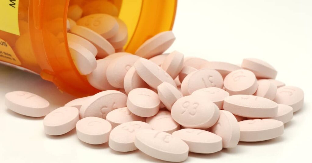 Prescription drugs poured out of a pill bottle | Burg Simpson