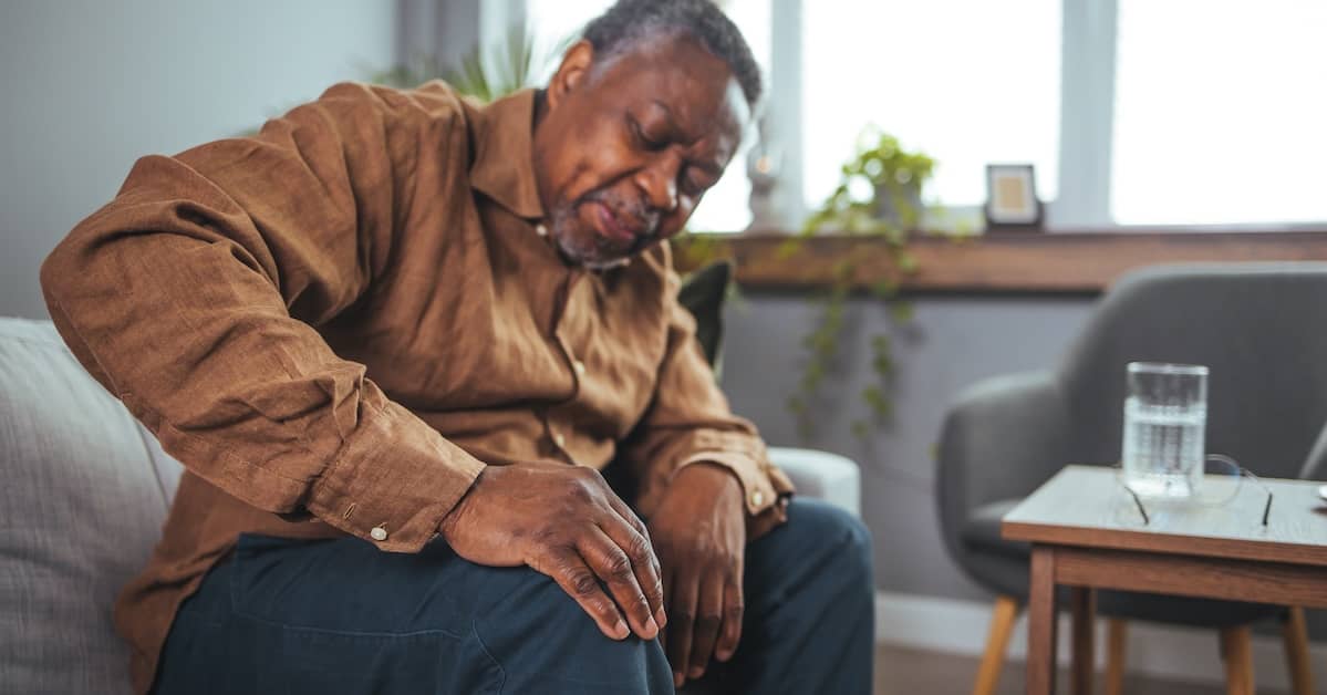 Elderly African-American man suffering with knee pain | Burg Simpson