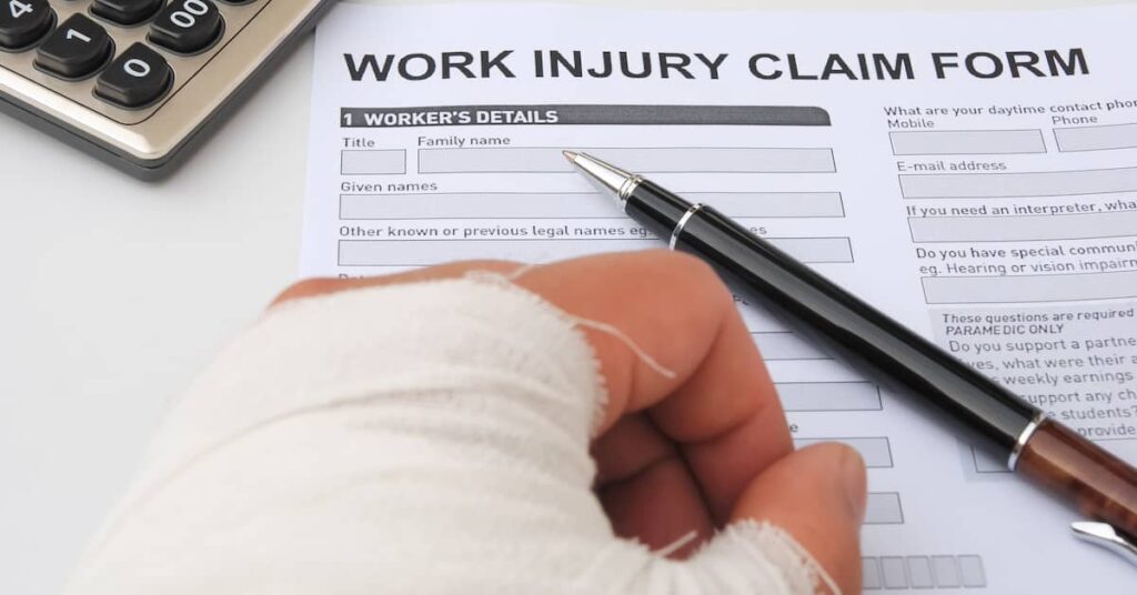 Worker with injured hand filling out Work Injury Claim Form document | Burg Simpson