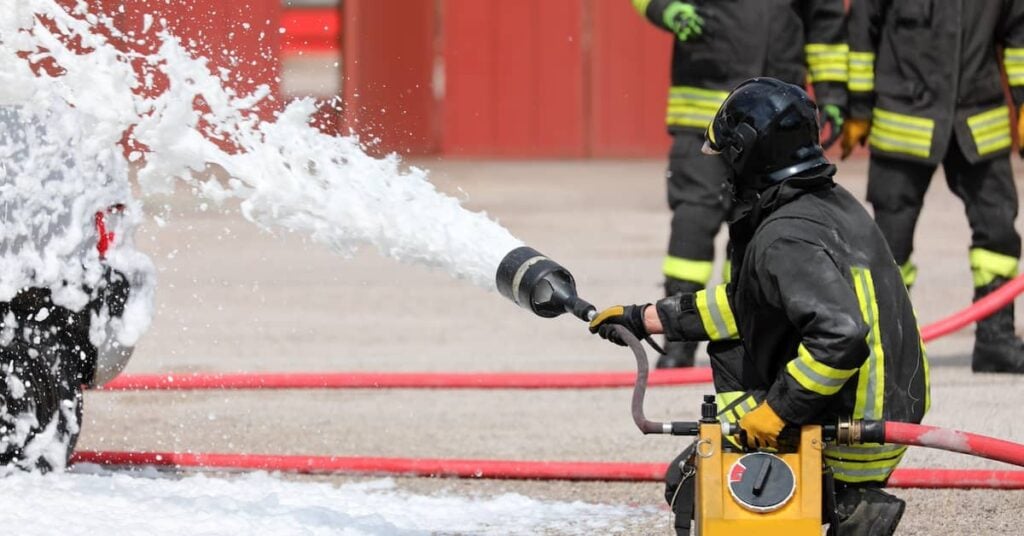 Firefighter using foam to put out a fire after a traffic accident | Burg Simpson Law Firm