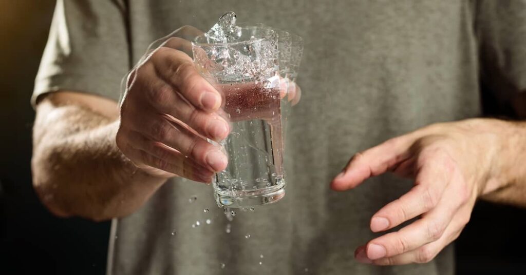 Man with Parkinson's disease tremor struggling to hold a glass of water | Burg Simpson Law Firm