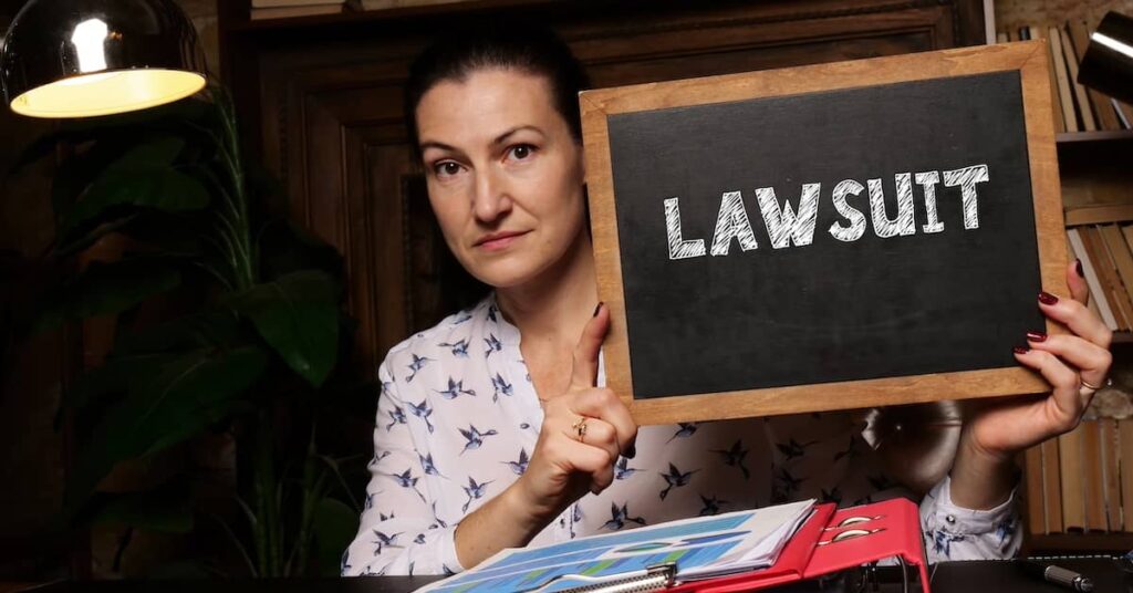 Class action plaintiff holding a chalkboard that says 'Lawsuit' | Burg Simpson