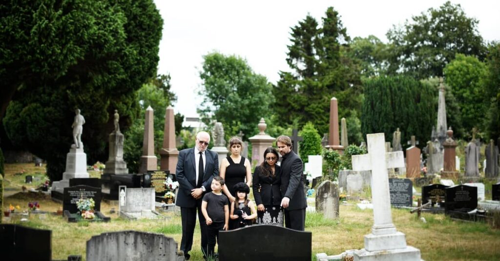 Family in cemetery at the grave of a deceased loved one | Burg Simpson