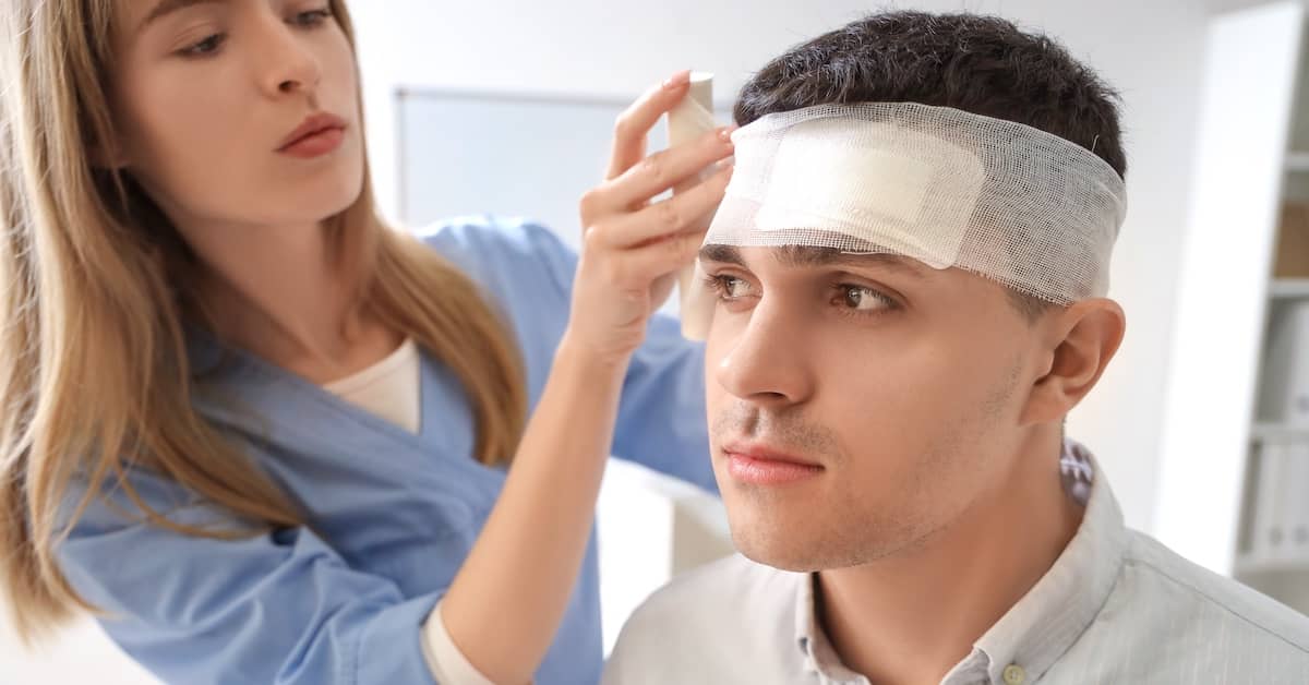 Young man receiving treatment for head injury | Burg Simpson