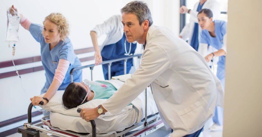 Doctors and nurses rushing patient into the emergency room | Burg Simpson
