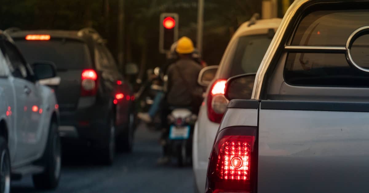 Lane filtering motorcycle in a line of cars at a red light | Burg Simpson