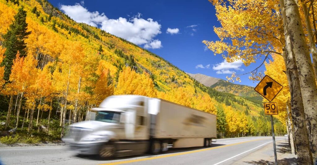 Tractor trailer truck driving along Colorado highway on colorful autumn day | Burg Simpson