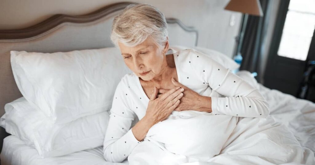 Elderly woman experiencing a medical emergency in bed at a nursing home | Burg Simpson