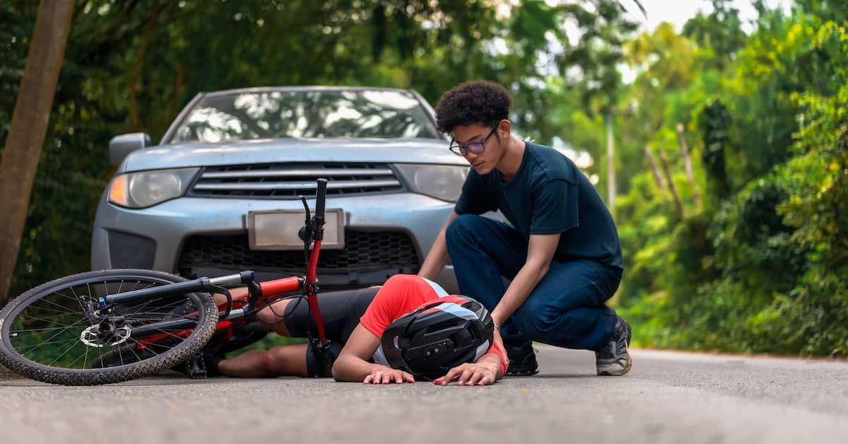 Young driver helping female bicyclist after hitting her with his car | Burg Simpson