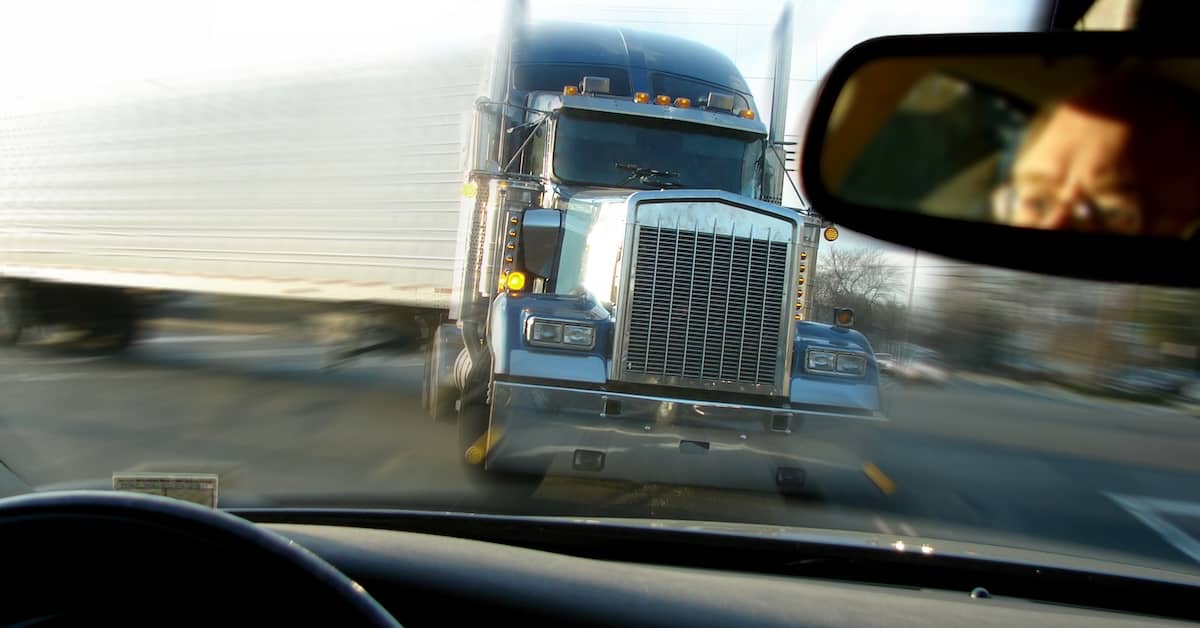 Male driver looking at a semi-truck about to hit him head on | Burg Simpson