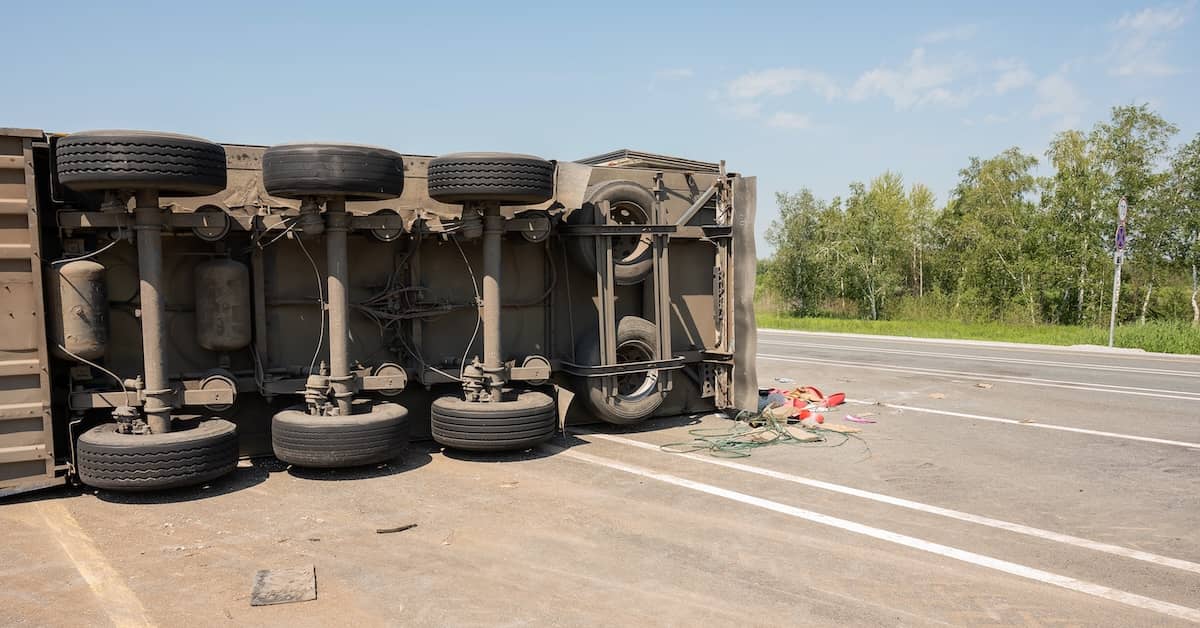 Overweight truck tipped over on its side in the roadway | Burg Simpson