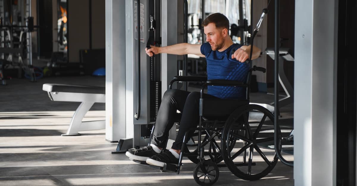 Man in wheelchair due to spinal cord injury exercising in the gym | Burg Simpson