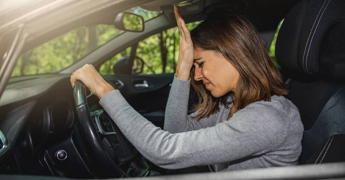 Woman pressing her hand to a forehead after a head injury in a car accident | Burg Simpson