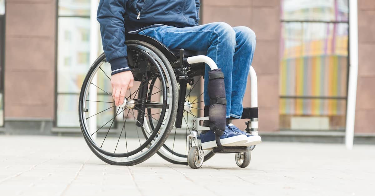 Man with a spinal cord injury using his wheelchair on the sidewalk | Burg Simpson