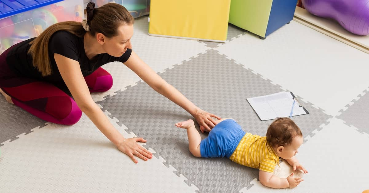 Young woman helping baby crawl | Burg Simpson