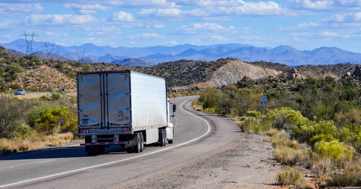 Semi-truck driving along a desert road in Arizona | Burg Simpson