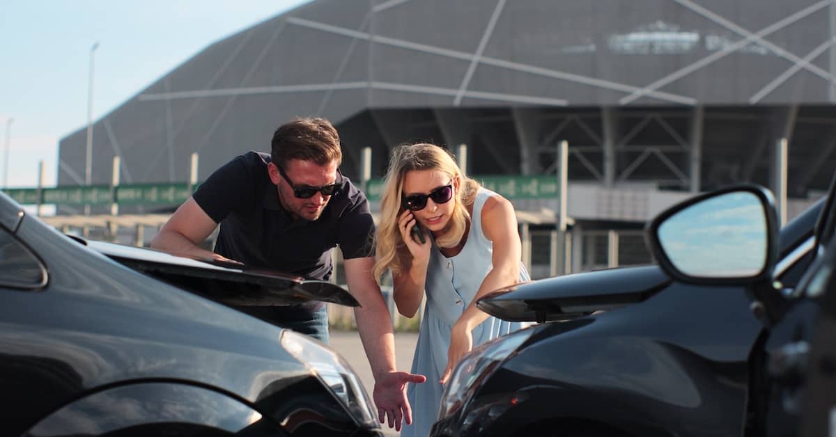 Man and woman assessing the damage from a car accident | Burg Simpson